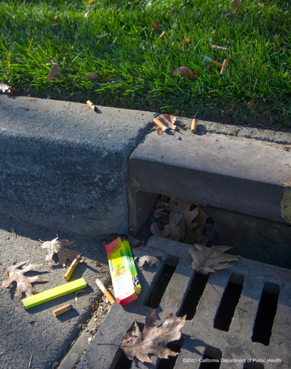 shows gutter with cigarette butts and vape pen